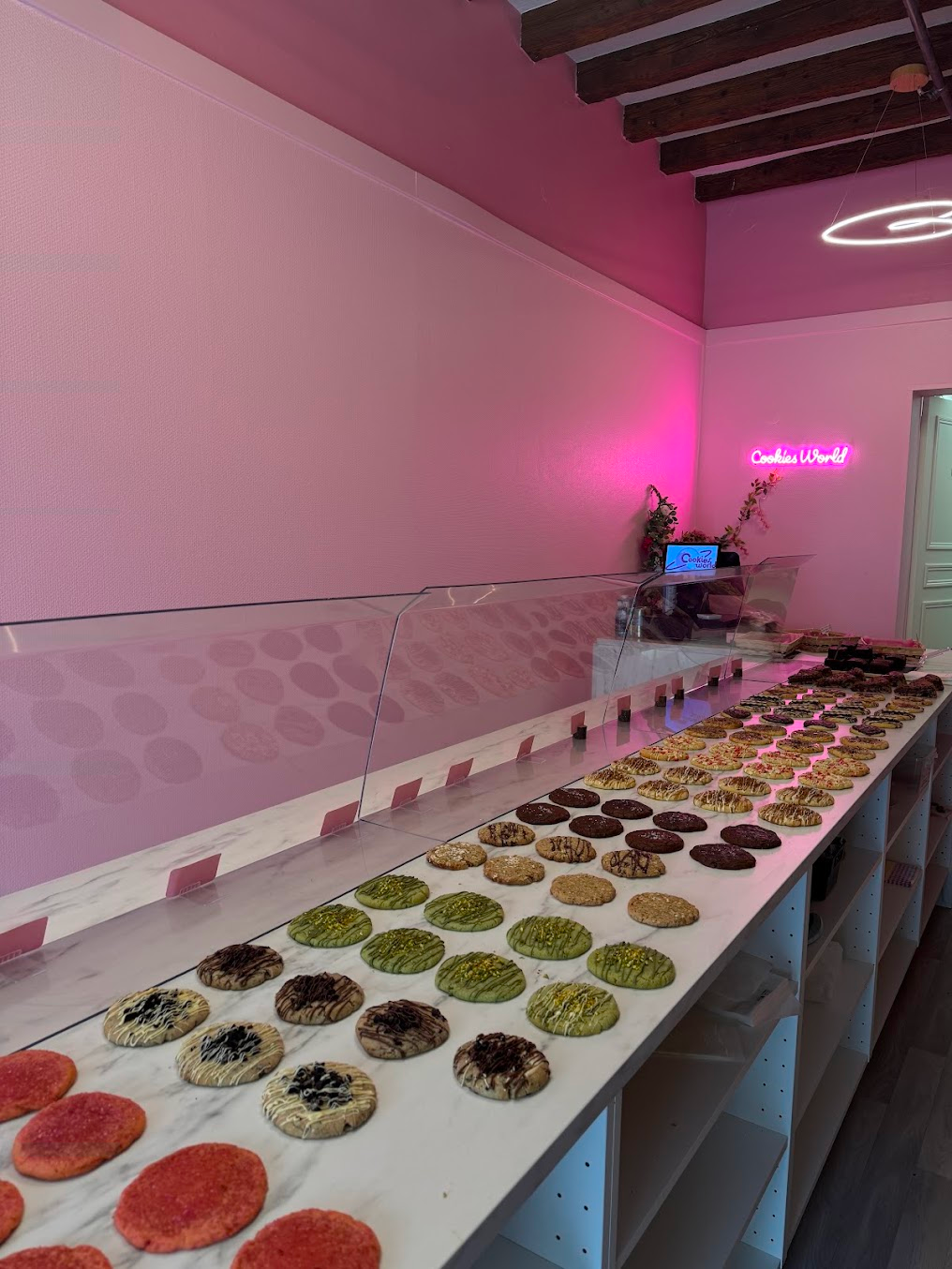 Intérieur de la boutique Cookies World : murs roses, enseigne néon et comptoir garni de cookies