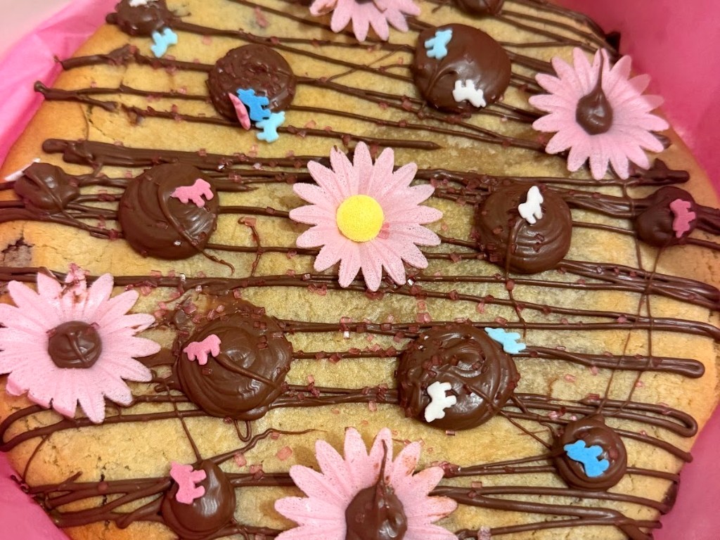Cookie géant décoré de chocolat, de fleurs en sucre roses et de vermicelles